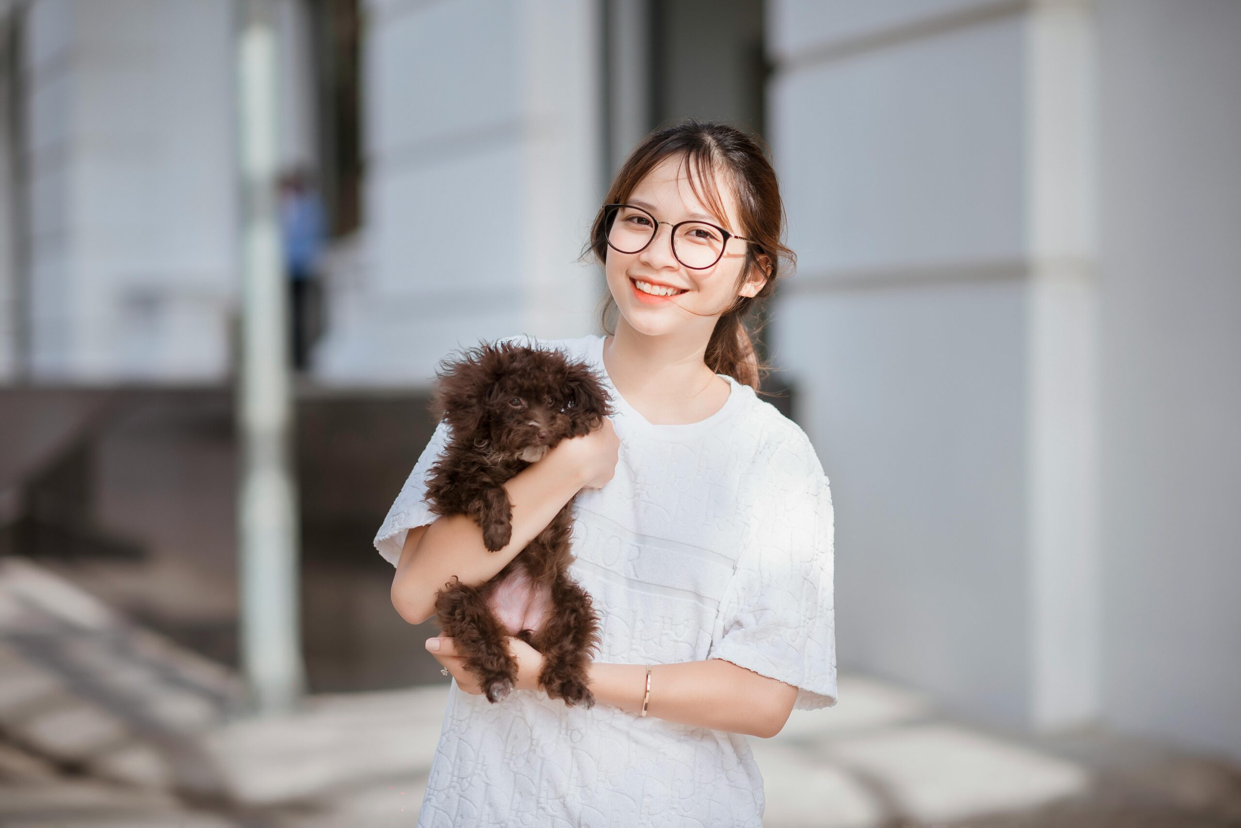 A Girl Holding a Puppy and Smiling